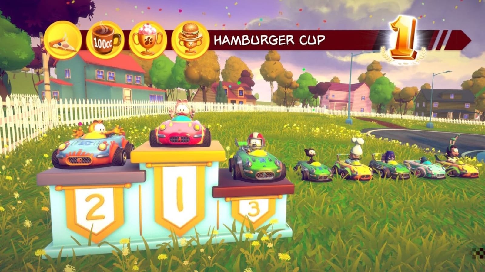 Cena de jogo com pódio numerado 1, 2 e 3 em bairro com casas, cercas brancas e campo com flores amarelas. No pódio: Arlene em kart rosa em primeiro lugar, Garfield em kart laranja em segundo e Odie em kart verde em terceiro. Outros corredores aparecem alinhados ao lado.