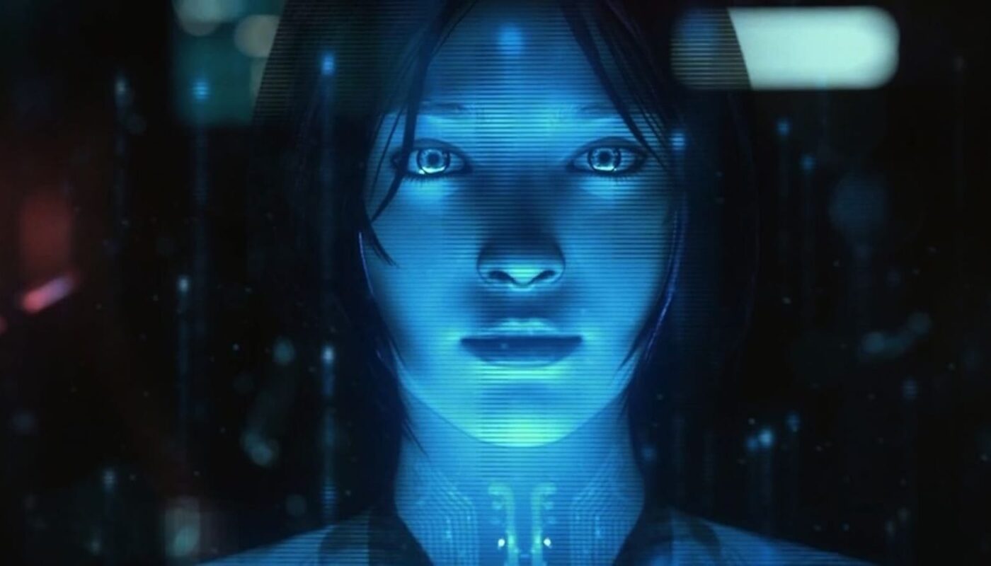 Rosto humanoide holográfico em tons de azul, formado por luz translúcida sobre fundo escuro com partículas brilhantes.