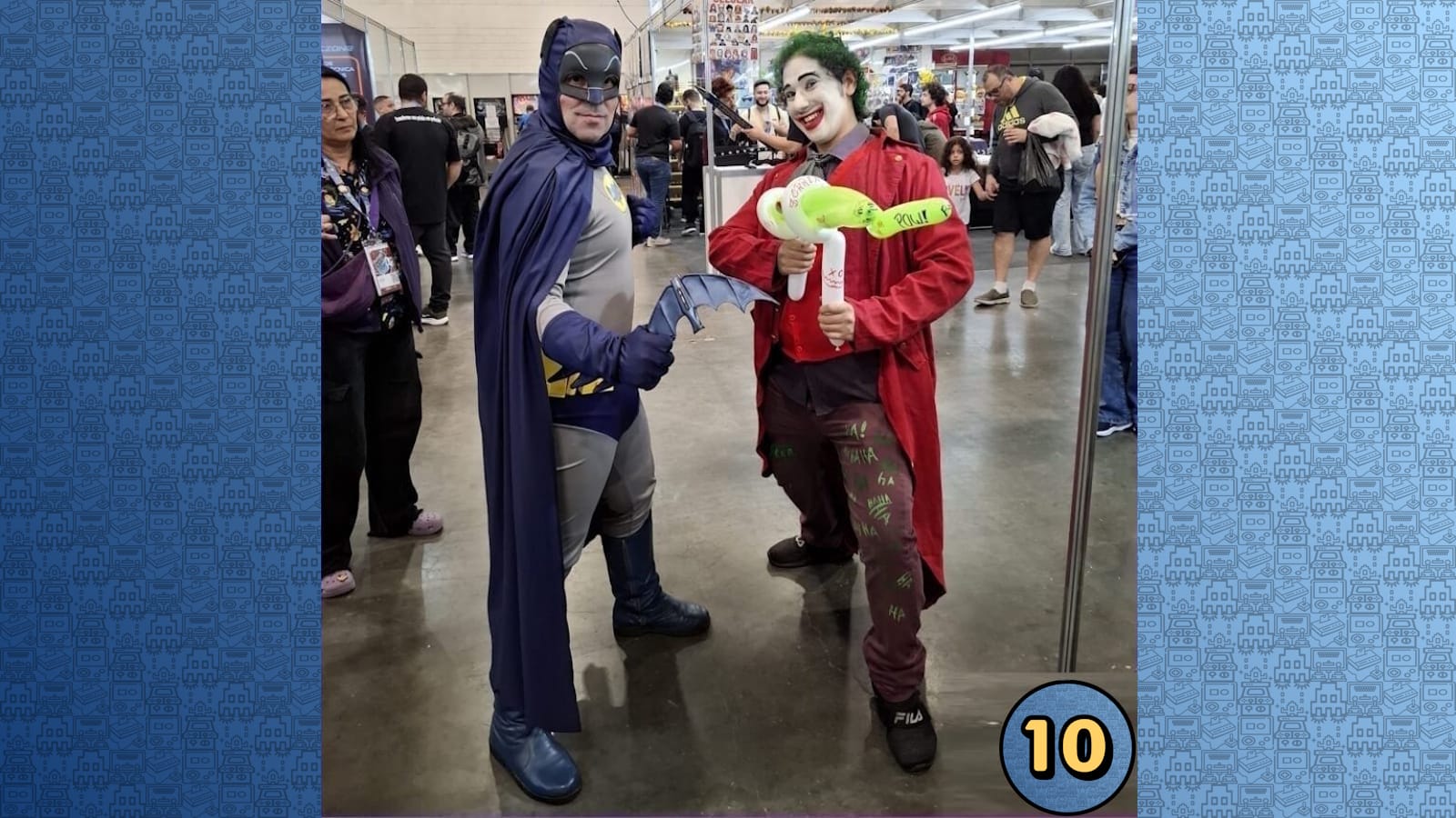 Cosplayers de Batman e Coringa posam juntos em evento. Batman usa traje preto com capa; Coringa veste casaco vermelho, cabelo verde e maquiagem branca. 