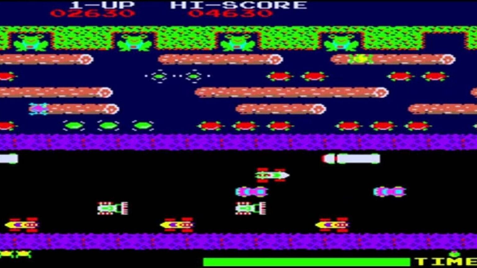 Tela de Frogger com sapo atravessando estrada cheia de veículos e rio com troncos e tartarugas, pontuações exibidas no topo.