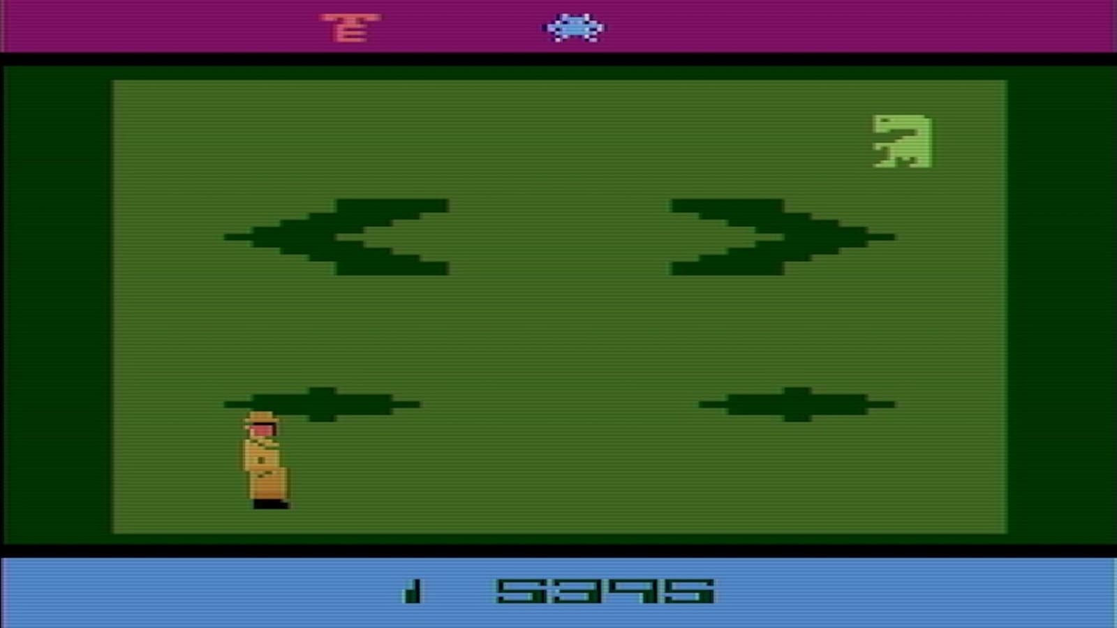 Tela de jogo Atari com personagem marrom à esquerda, criatura verde à direita, obstáculos centrais e barra inferior exibindo pontuação.