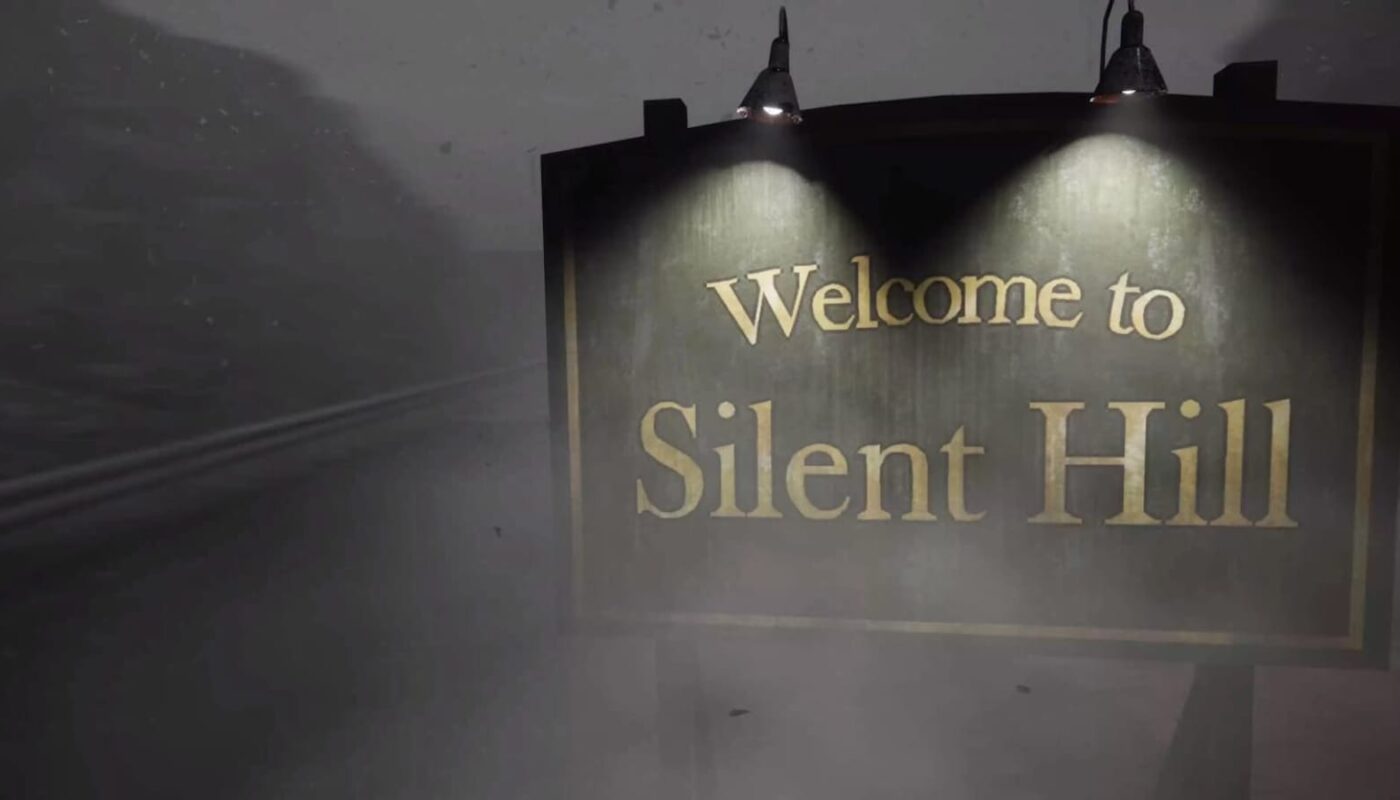 Placa iluminada por duas lâmpadas com texto ‘Welcome to Silent Hill’ diante de estrada coberta por névoa, com silhuetas de montanhas ao fundo em clima sombrio.