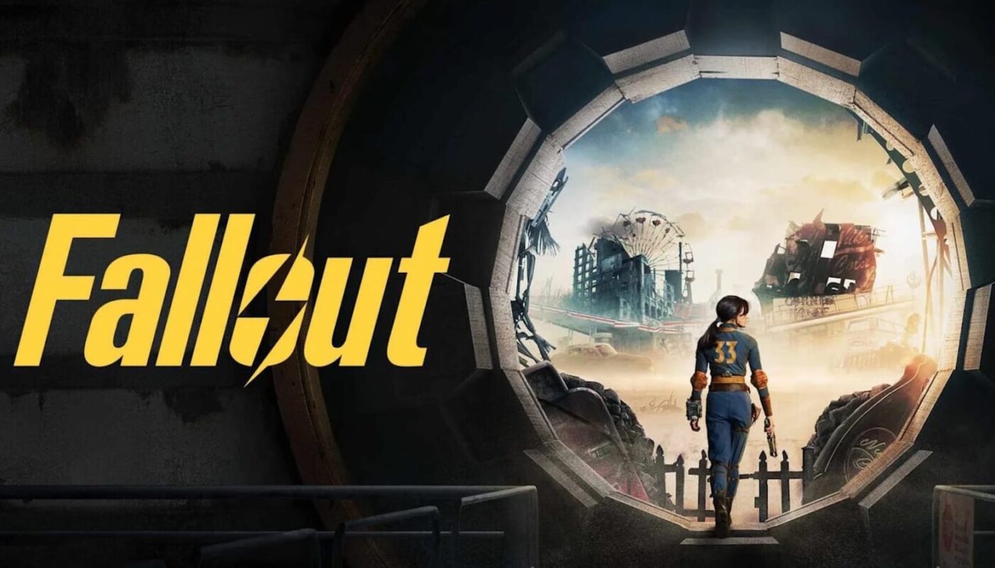 Arte promocional com palavra ‘Fallout’ em letras amarelas à esquerda. À direita, figura em macacão azul com número 33 nas costas caminha para fora de porta circular de cofre, entrando em paisagem destruída com prédios em ruínas, roda‑gigante danificada e cidade coberta de poeira.