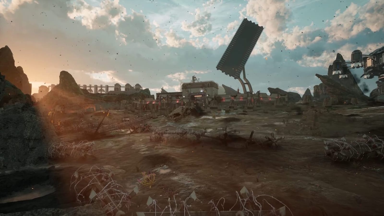 Paisagem sci‑fi com terreno acidentado e estrutura industrial enorme composta por painel inclinado sustentado por braços mecânicos. Arame farpado e destroços aparecem no primeiro plano. Ao fundo há plataformas elevadas e prédios conectados por pontes sob céu dramático iluminado pelo pôr do sol.